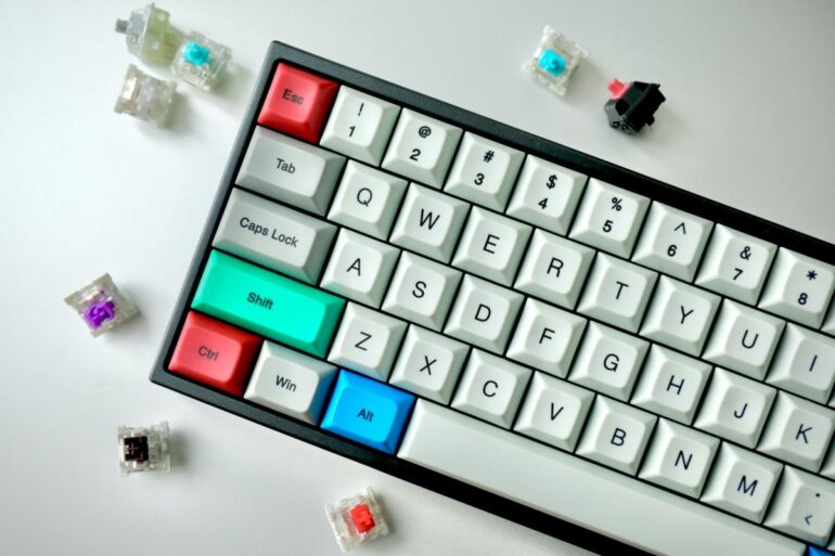 Compact mechanical keyboard with colorful modifier keys surrounded by different switch types for customizing typing feel.
