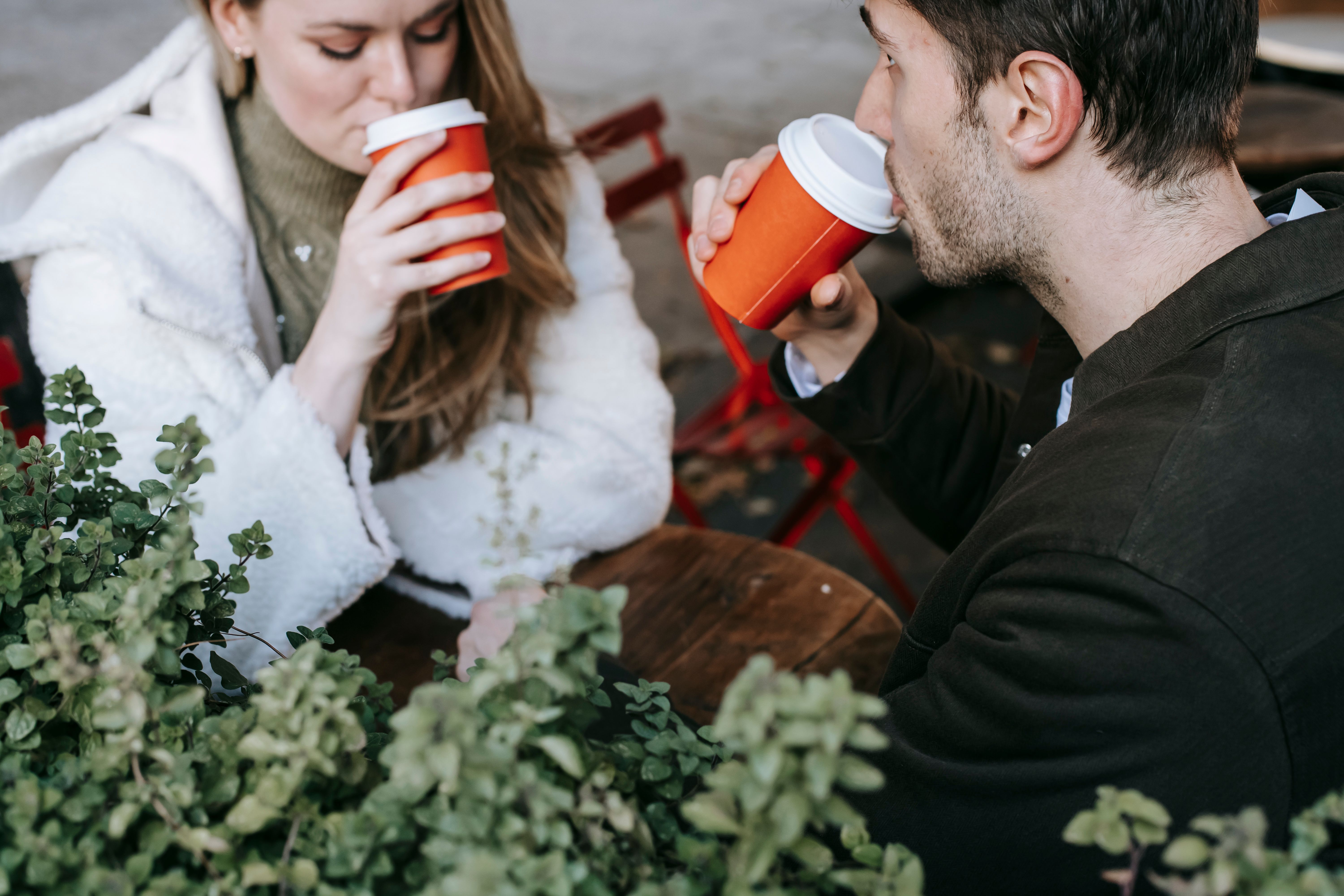 Two people sharing coffee at a street café, a relaxed image of companionship and connection.
