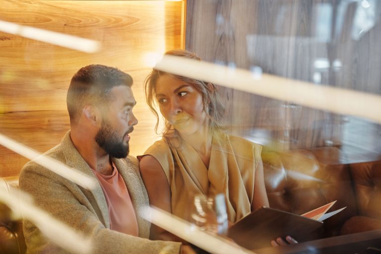 Two adults talking over dinner in a restaurant, illustrating paid companionship and changing ideas about intimacy.